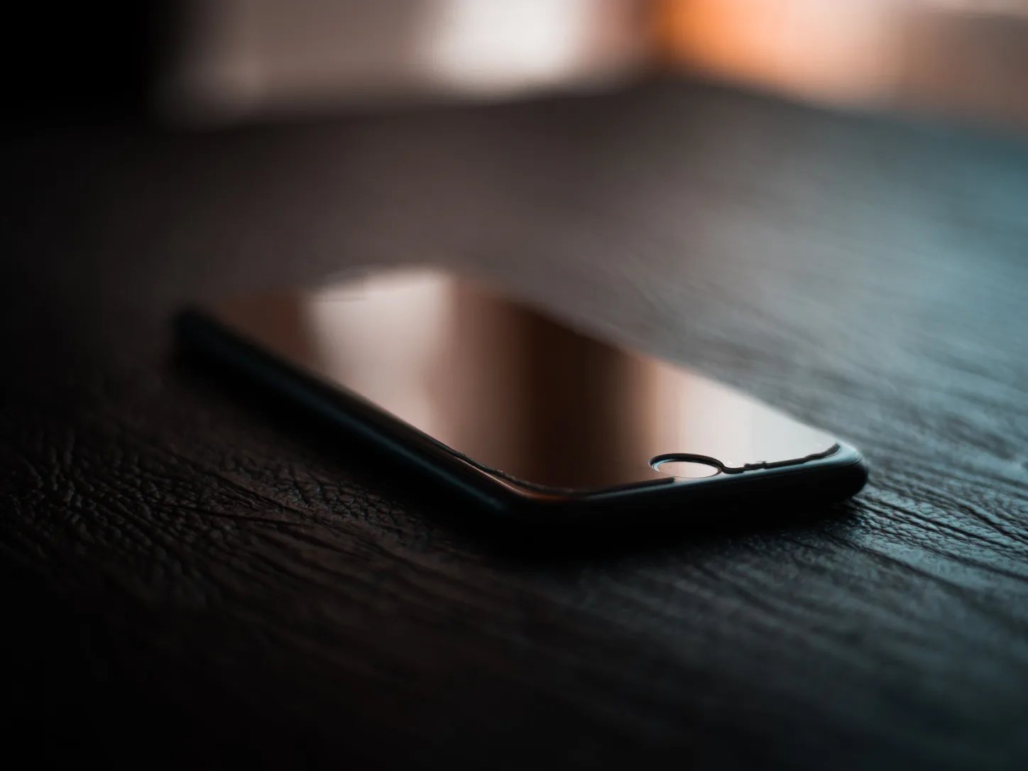 Telefon z wygaszonym ekranem odłożony na drewnianym stole