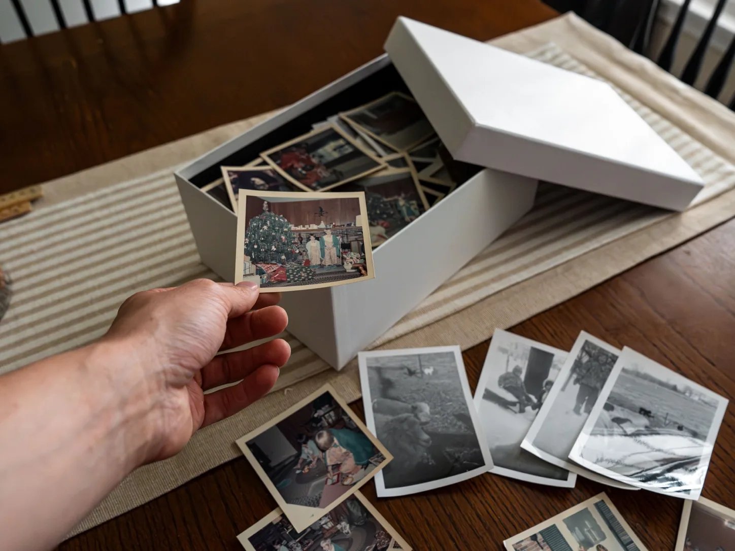 Dłoń przegląda rodzinne fotografie przechowywane w pudełku